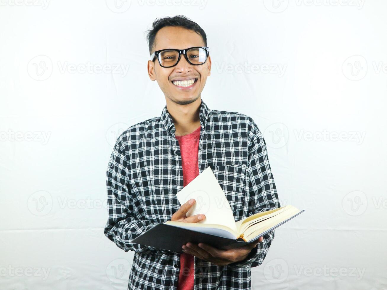 Beau asiatique étudiant souriant et en portant et en train de lire livre dans main photo