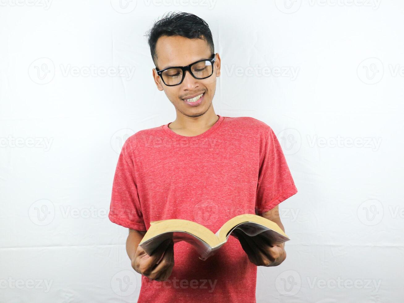 portrait de asiatique homme en portant livre avec en train de lire concentré expression. photo