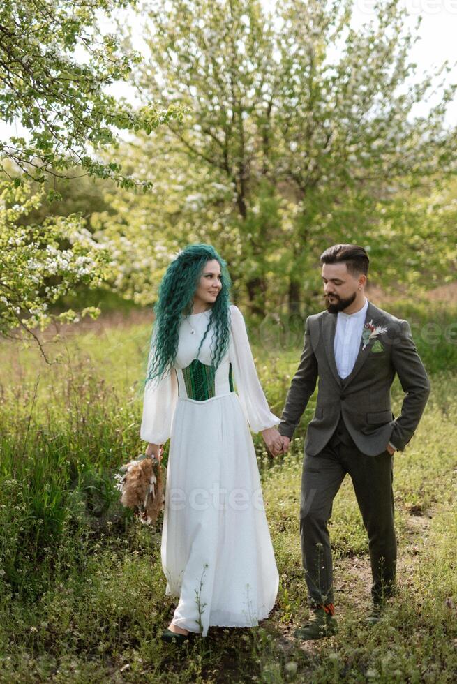 une barbu jeune marié et une fille avec vert cheveux sont en marchant photo