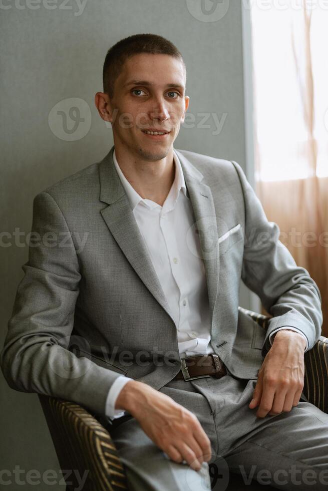 portrait de une jeune marié dans une gris plaid costume avec une attacher dans une lumière bar photo