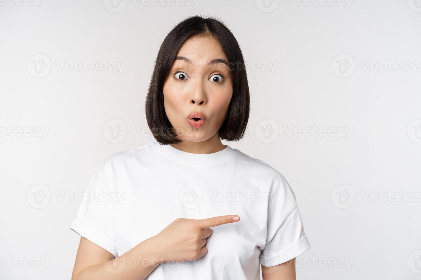 portrait de surpris asiatique femme dire Ouah, montrer du doigt droite à incroyable produit offre, vente ou logo, permanent plus de blanc Contexte photo