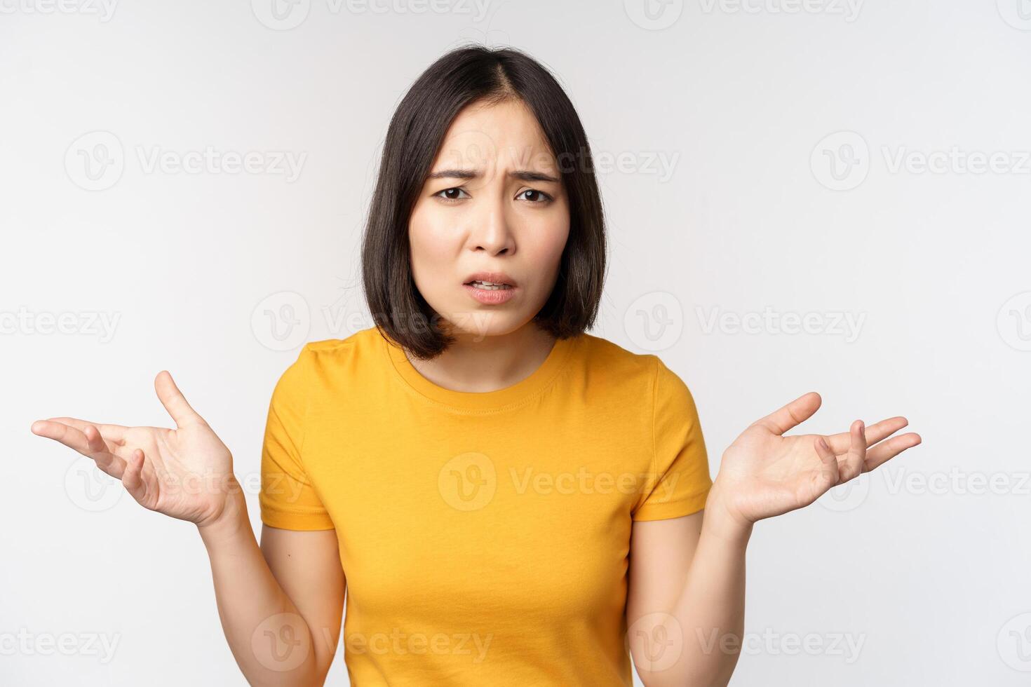 frustré, confus asiatique femme cant comprendre qch, à la recherche désemparés, haussant les épaules épaules, permanent dans Jaune T-shirt plus de blanc Contexte photo