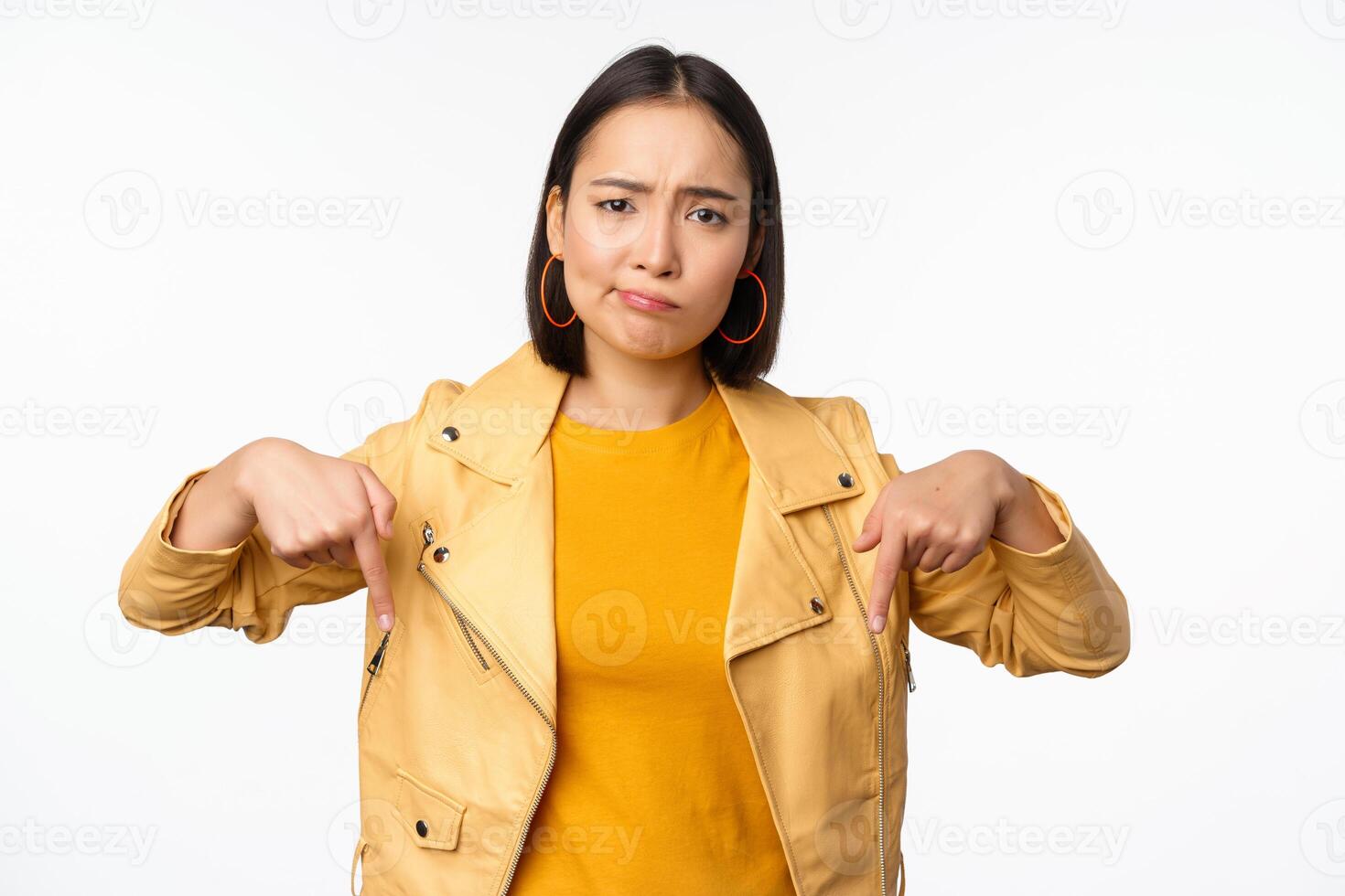 portrait de déçu asiatique femme montrer du doigt les doigts bas, grimaçant et montrant qch mauvais, permanent plus de blanc Contexte photo