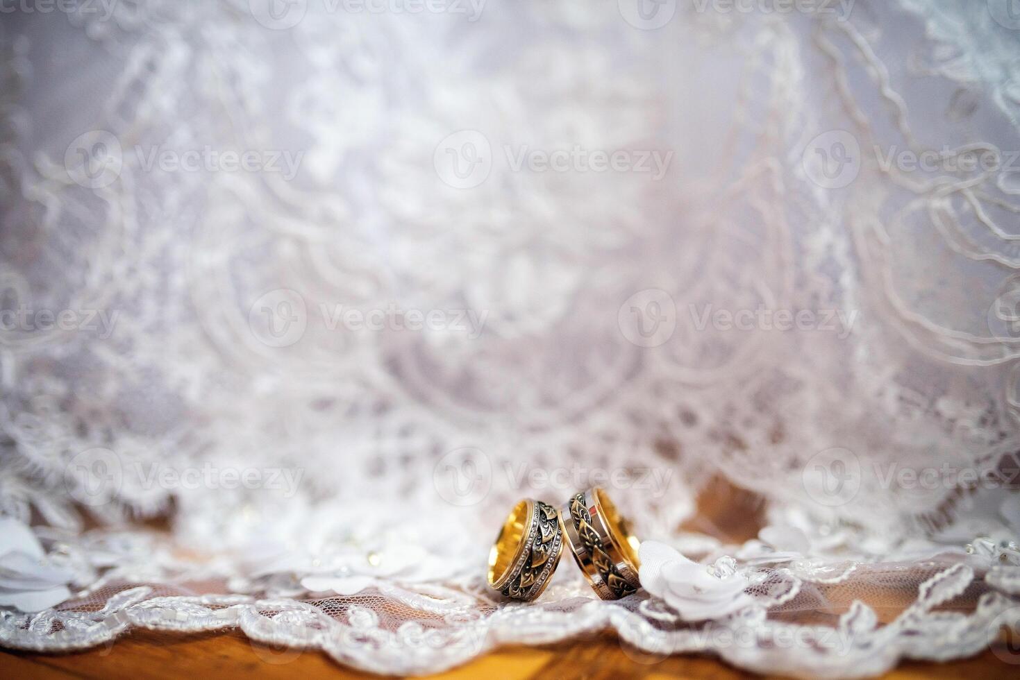 deux élégant mariage anneaux sur une blanc robe Contexte. romantique accessoires pour la mariée et jeune marié. mariage bijoux. fermer photo