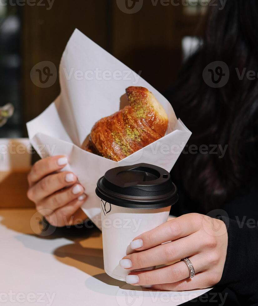 fille en mangeant croissant avec pistache poudre et en buvant café sur terrasse photo