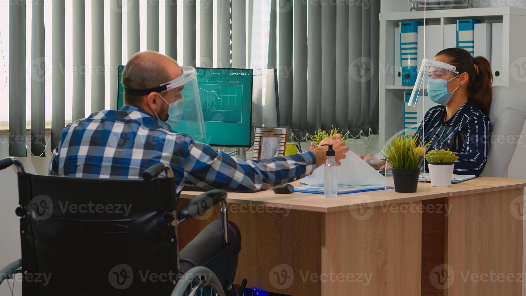 paralysé financier ouvrier dans fauteuil roulant avec protection masque travail dans Nouveau Ordinaire affaires Bureau parlant avec collègue. immobilisé pigiste dans entreprise entreprise respectant social distance. photo