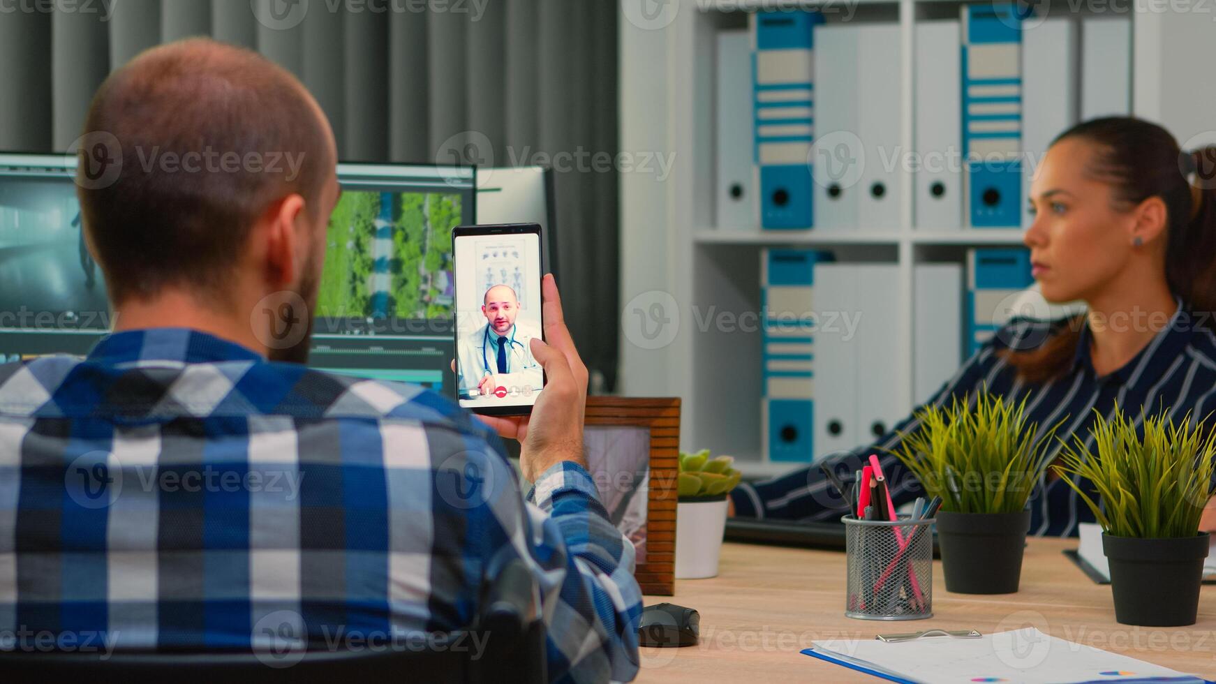 désactivée free-lance vidéaste parlant sur vidéo appel avec médecin dans travail temps tandis que crée contenu séance dans fauteuil roulant dans moderne entreprise bureau. créateur blogueur travail de photo studio.