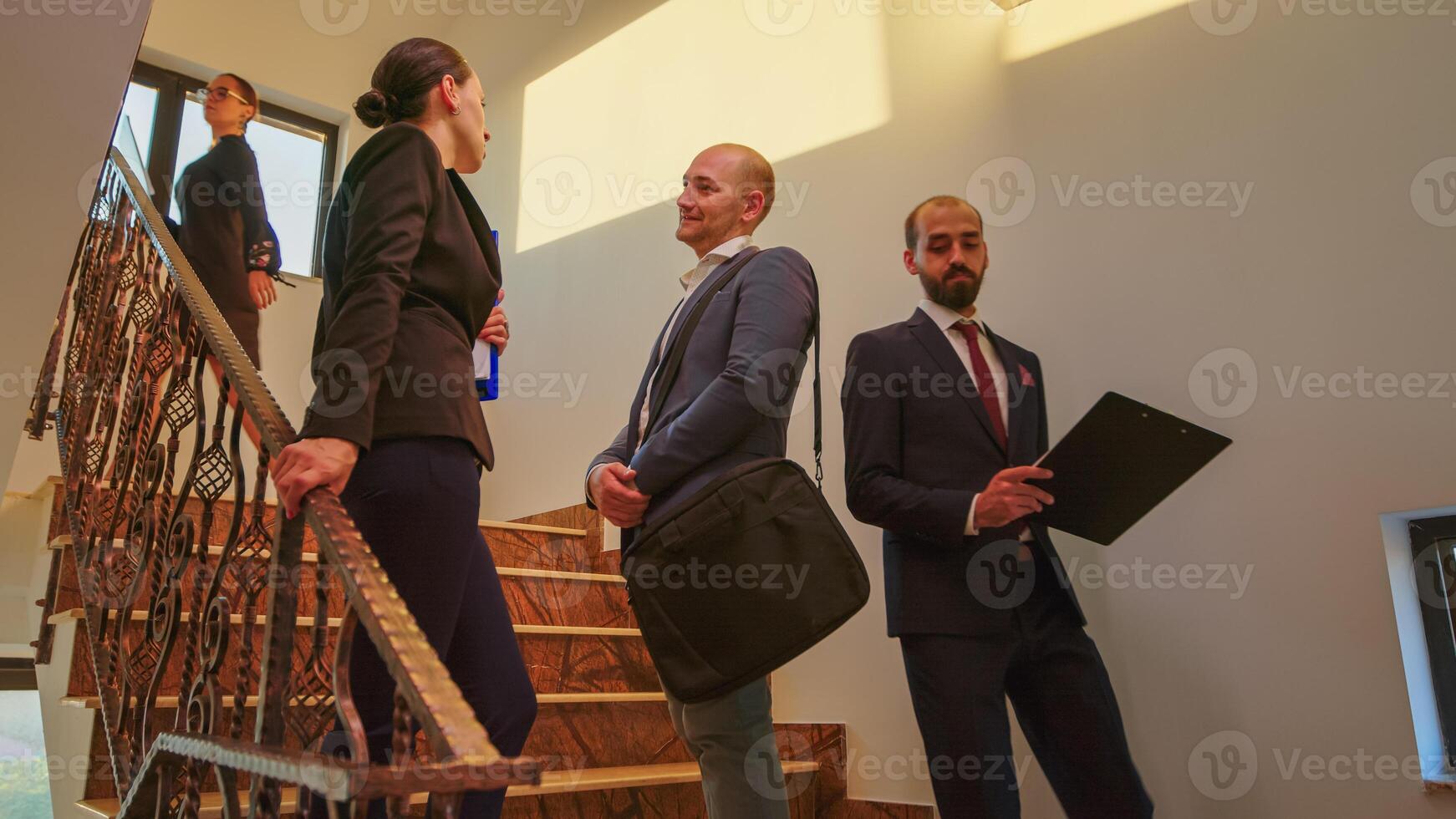 homme d'affaire et attrayant collaborateur permanent sur escaliers parlant et souriant dans Bureau entreprise bâtiment. groupe de professionnel réussi hommes d'affaires travail ensemble dans moderne financier lieu de travail. photo