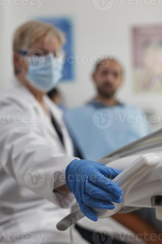 fermer de Sénior femme dentiste travail à les dents procédure pour patient avec mal aux dents en utilisant professionnel dentaire instrument pendant stomatologique consultation dans dentisterie bureau. médicament un service photo