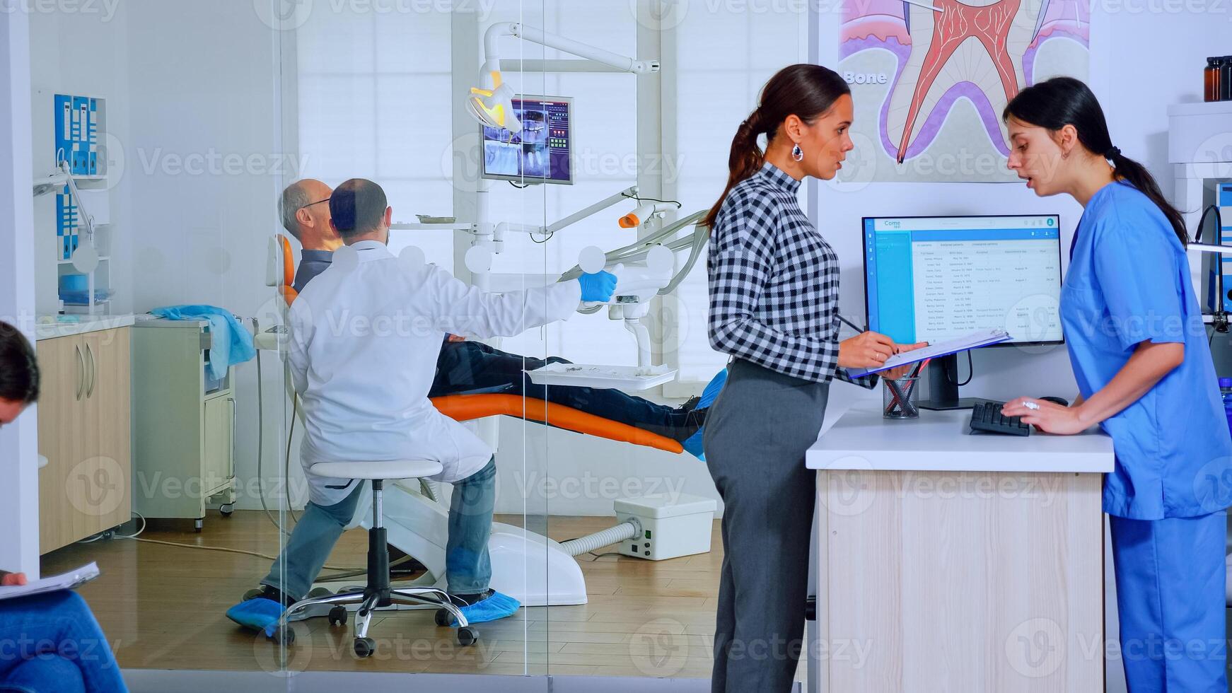 les patients demander informations remplissage dans dentaire document en train de préparer pour les dents examen. Sénior femme séance sur chaise dans attendre zone de bondé orthodontiste Bureau tandis que médecin travail dans Contexte photo