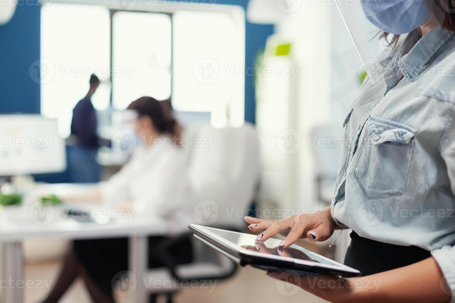 proche en haut de financier analyste vérification graphiques de gros société en utilisant tablette pc. Multi-éthnique collègues de travail respectant social distance dans affaires entreprise pendant coronavirus pandémie. photo