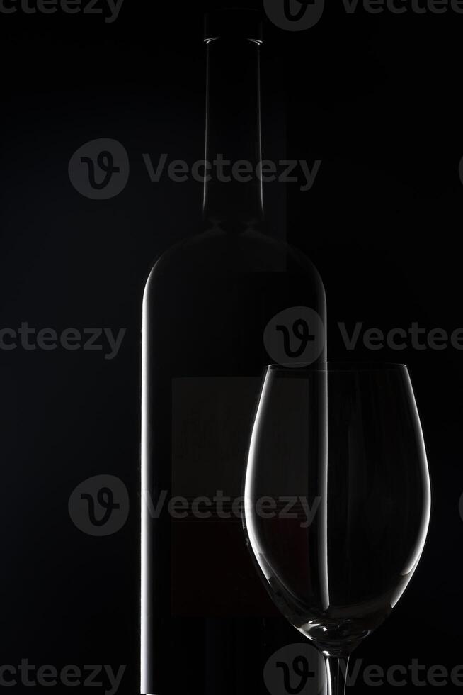 une verre de du vin et une bouteille de du vin sur une noir Contexte photo