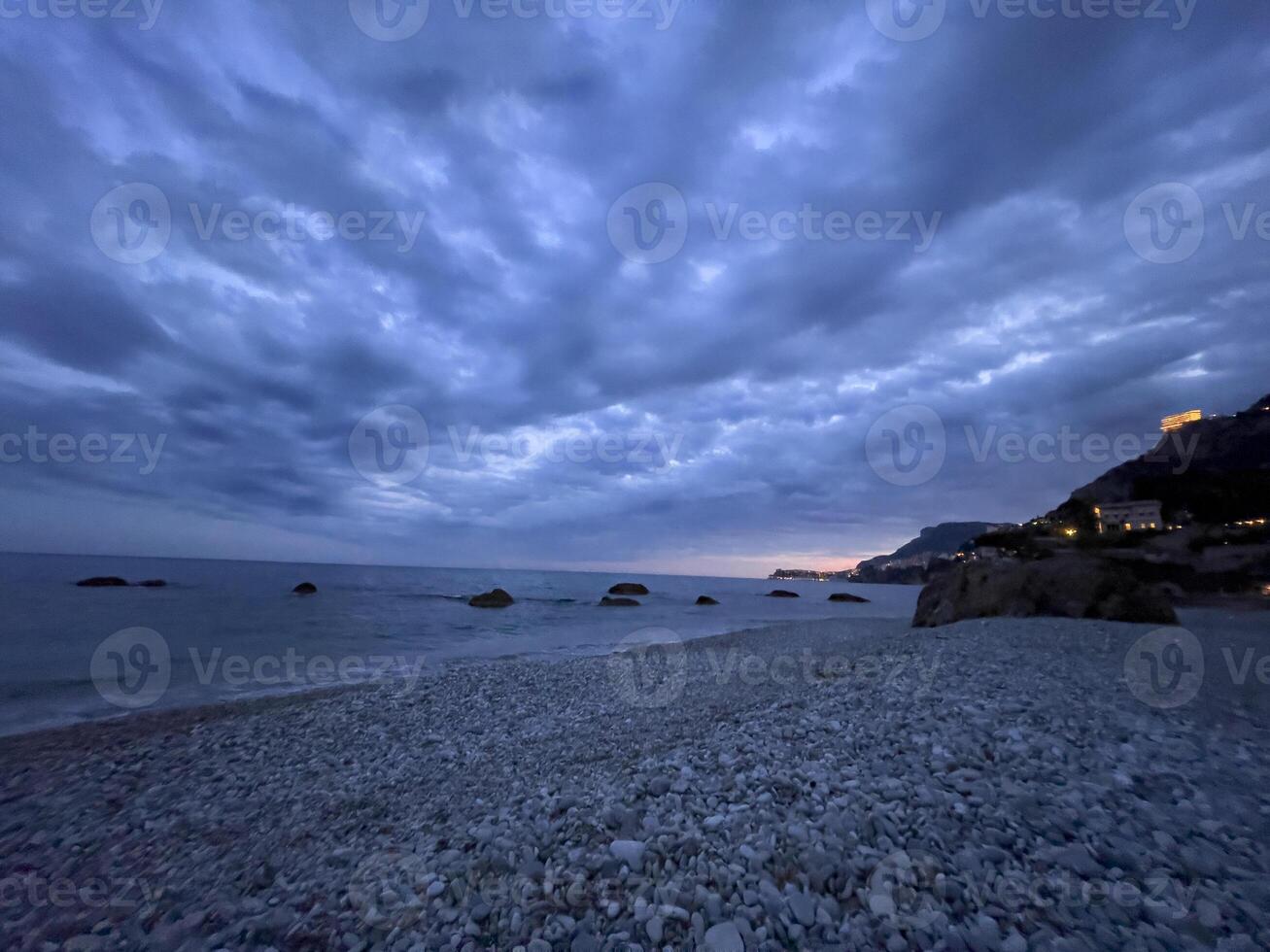 une plage à crépuscule avec des nuages et rochers photo