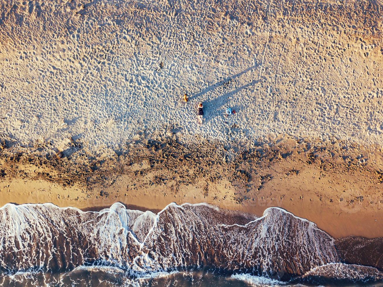 fille et chien à la plage au coucher du soleil, vues aériennes photo