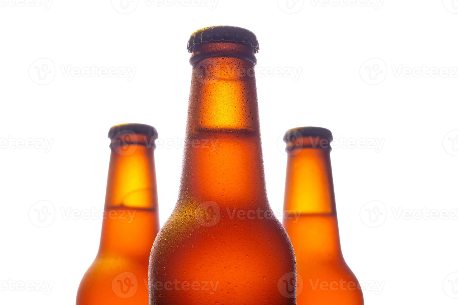 trois bouteilles de bière fraîche avec de petites gouttes d'eau sur fond blanc photo
