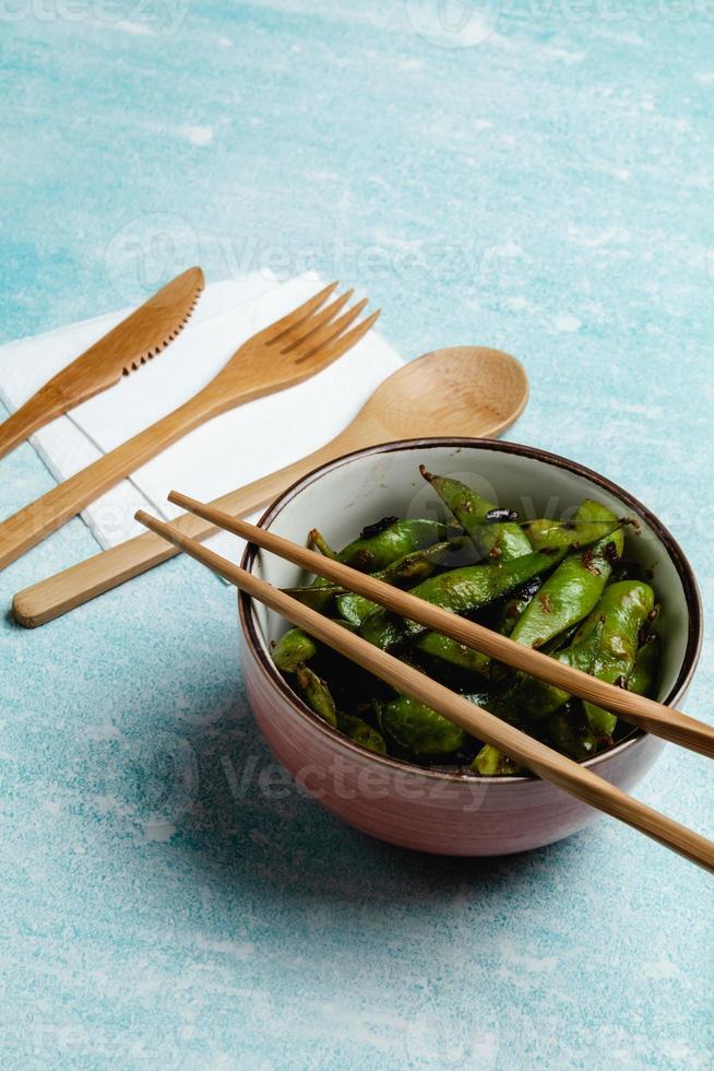 edamame cuit sur une table bleue. gousses de soja à grignoter photo