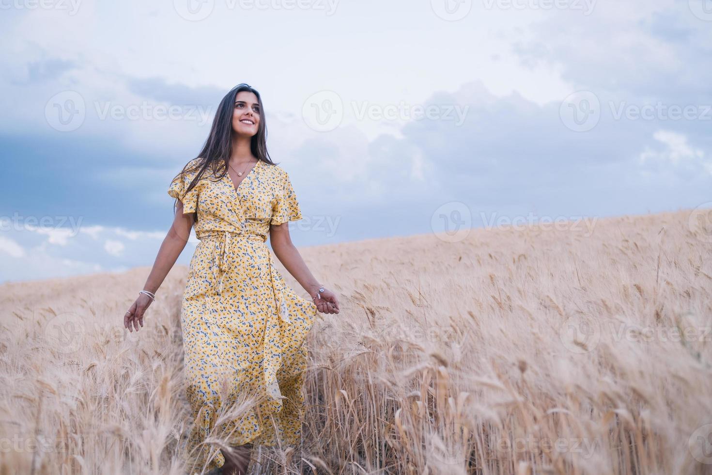 jeune femme joyeuse profitant de la nature en marchant dans un champ de blé. photo