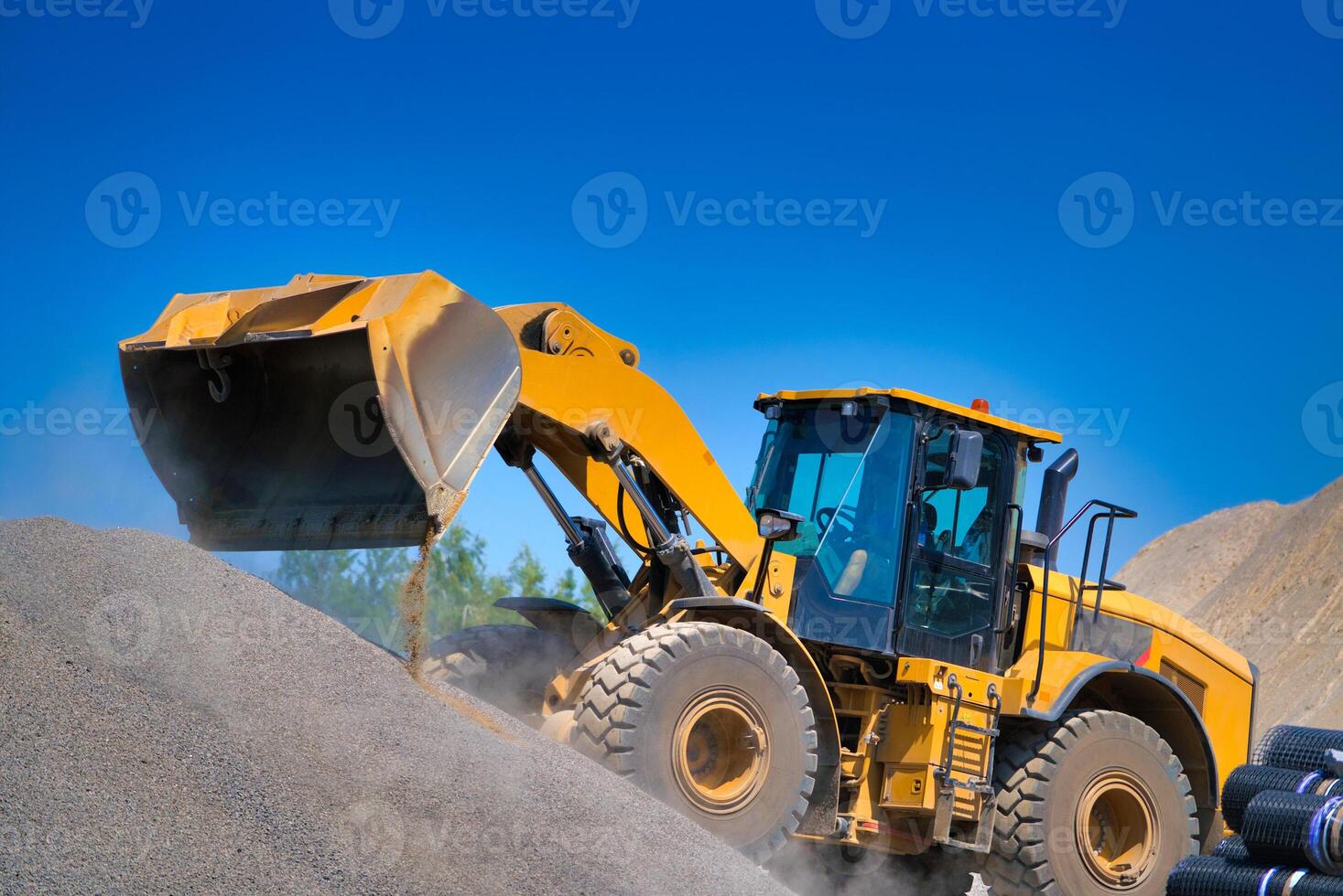 le tracteur recueille une scoop avec gravier. excavatrice extraits le sable et gravier pour le béton mélanger. photo