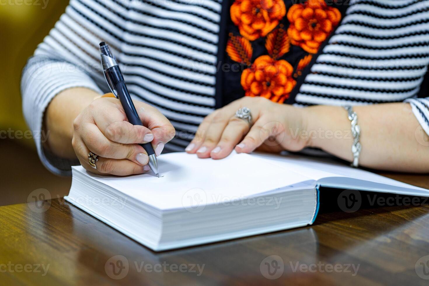 femelle mains avec stylo l'écriture dans une livre. fermer. photo
