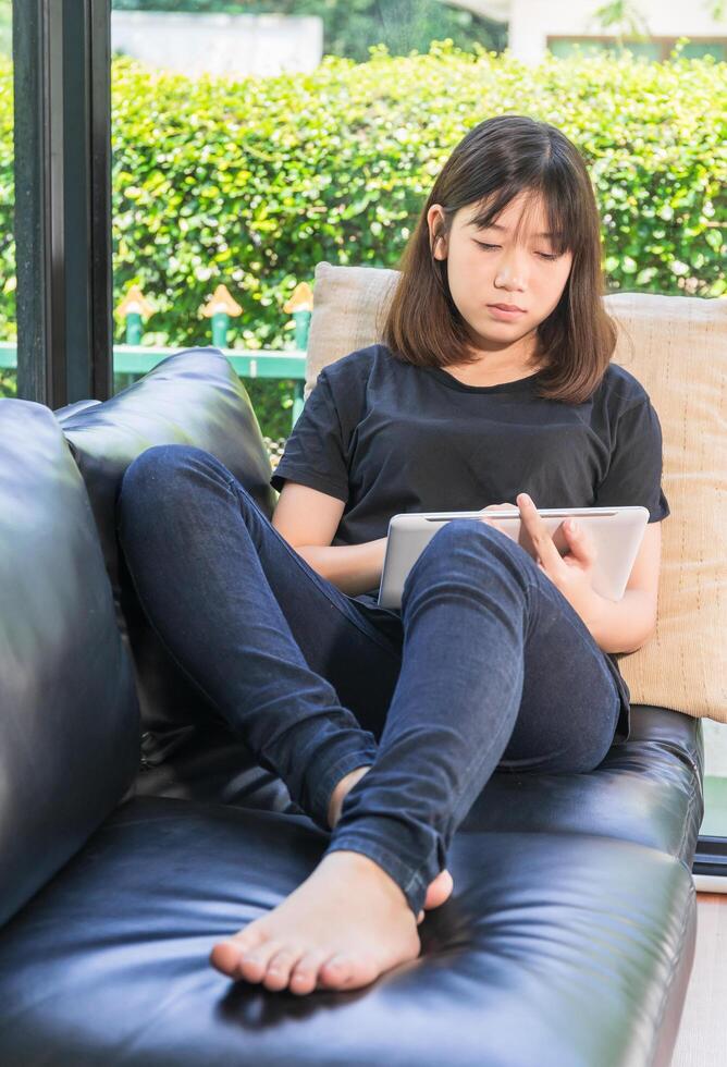 jeune fille étudiant en ligne à partir d'une tablette numérique dans le salon photo