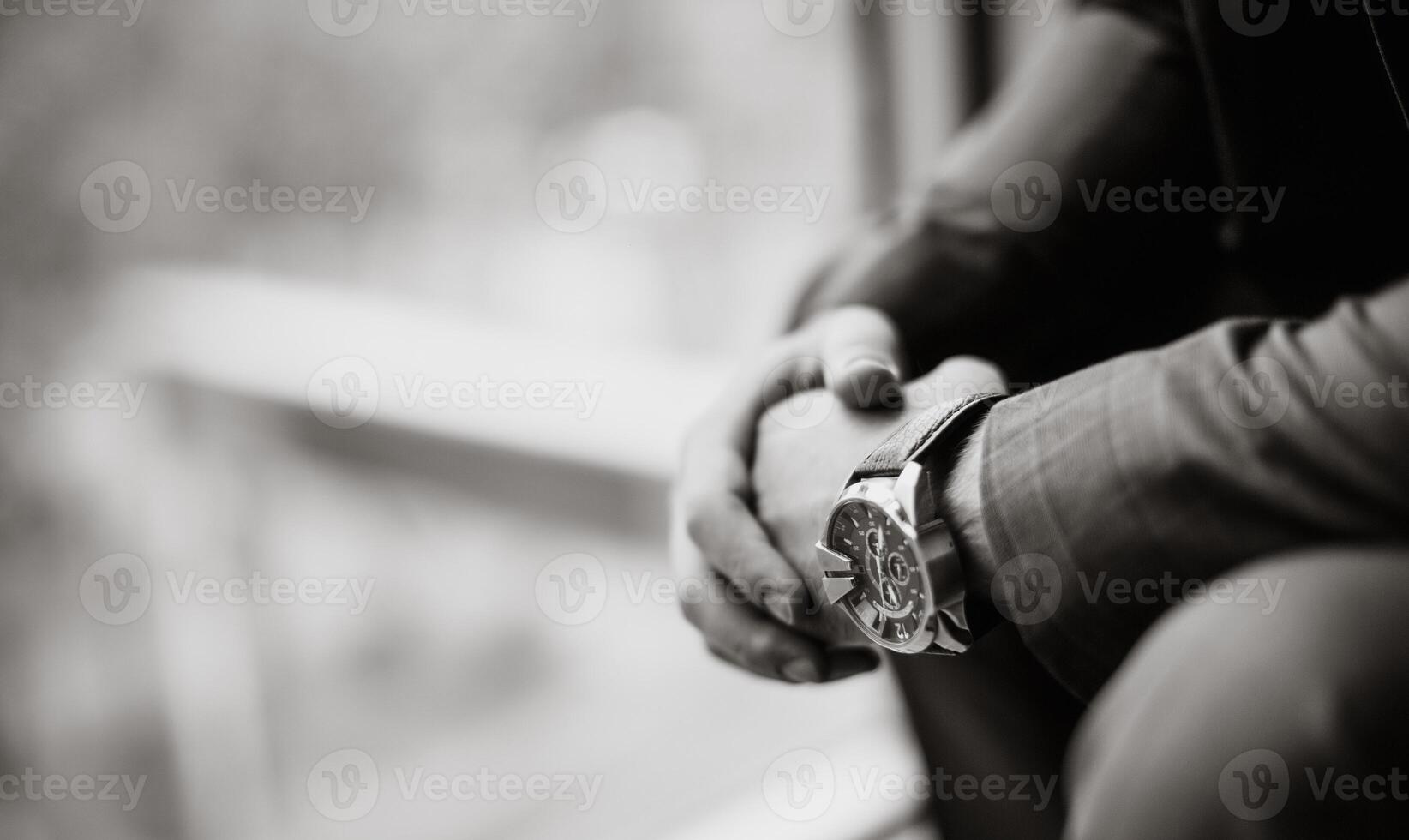 noir et blanc photo de une homme d'affaire dans une costume avec une regarder sur le sien main. flou Contexte. fermer