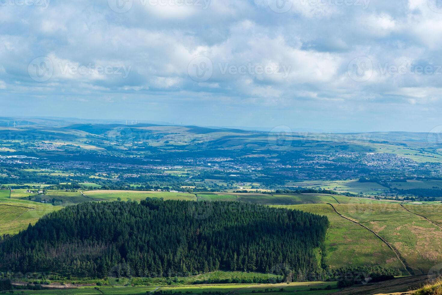 Stupéfiant aérien vue de luxuriant vert paysage avec forêt et roulant collines en dessous de une nuageux ciel. photo