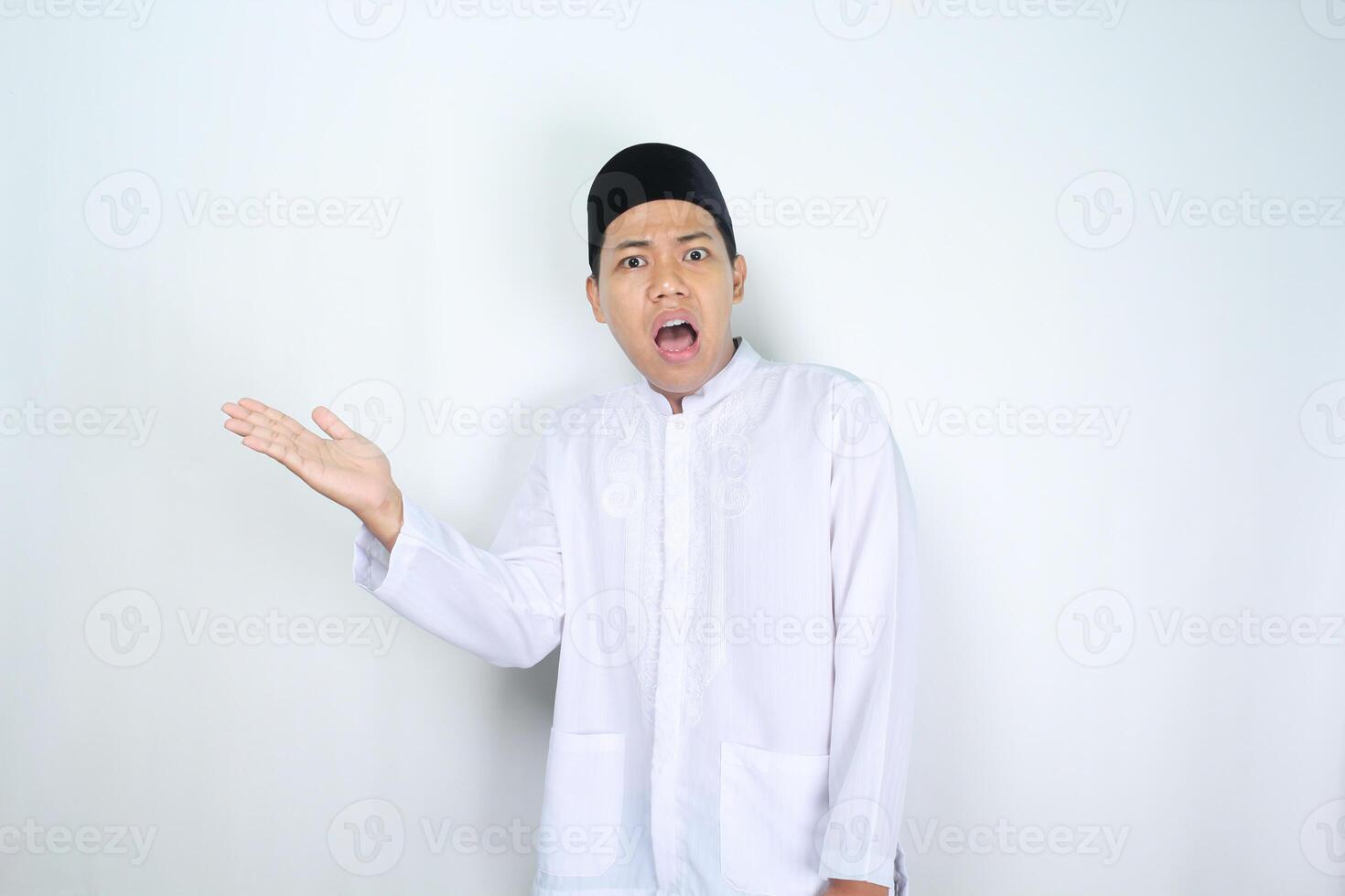 asiatique homme musulman élevage paume en présentant à à côté de avec sous le choc visage expression isolé sur blanc Contexte photo