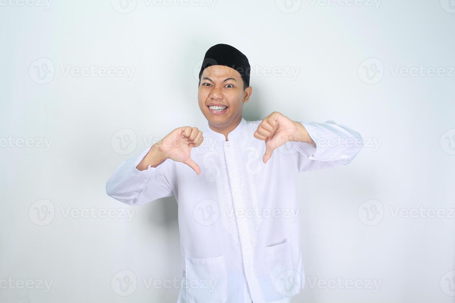 marrant musulman asiatique homme donnant les pouces vers le bas isolé sur blanc Contexte photo