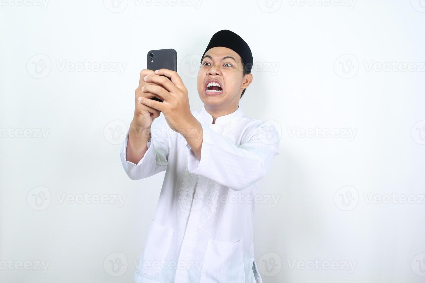 asiatique musulman homme spectacle en colère expression tandis que envoyer des SMS avec le sien téléphone photo