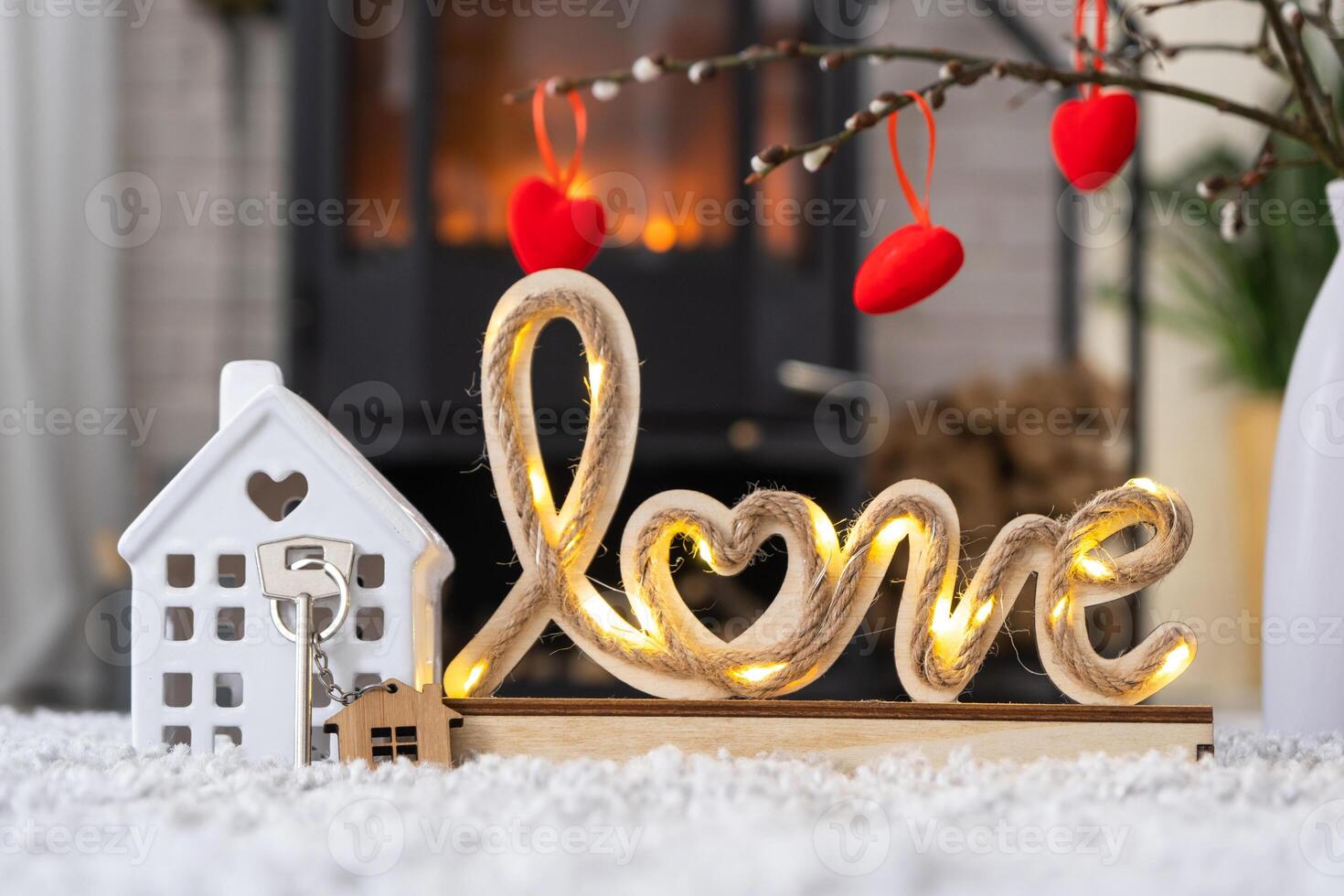 clé de la maison avec porte-clés sur fond de poêle cheminée avec feu et bois de chauffage dans un décor de saint valentin, love home. déménagement dans une nouvelle maison, hypothèque, location et achat immobilier photo