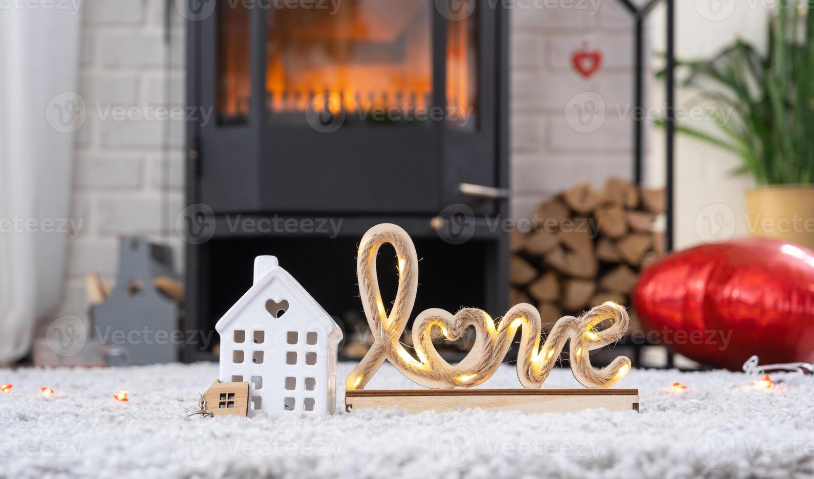 clé de la maison avec porte-clés sur fond de poêle cheminée avec feu et bois de chauffage dans un décor de saint valentin, love home. déménagement dans une nouvelle maison, hypothèque, location et achat immobilier photo