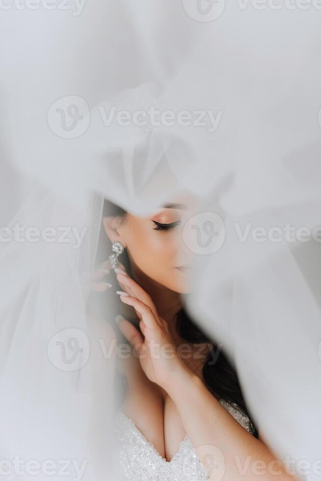 portrait de le la mariée dans le Hôtel chambre. une magnifique Jeune fille est habillé dans une blanc mariage robe. moderne mariage coiffure. Naturel se maquiller. photo