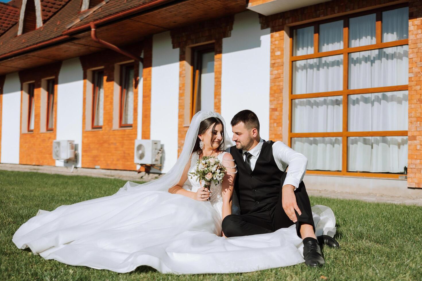 magnifique couple séance et étreindre en plein air sur leur mariage jour, relaxant sur le meilleur été journée. une Beau jeune marié et un élégant la mariée dans une magnifique mariage robe. photo