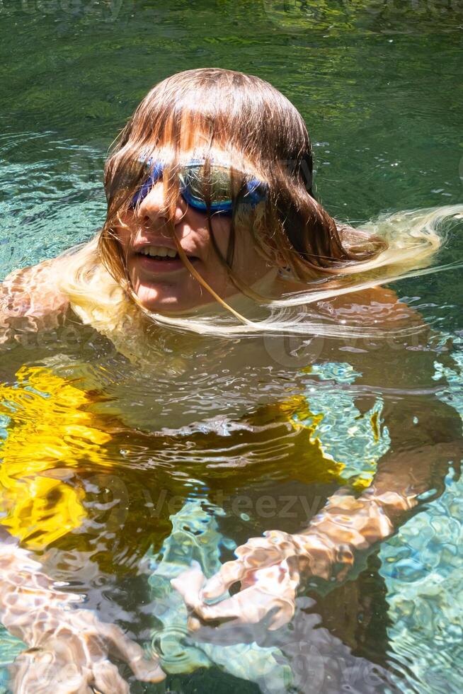portrait de marrant adolescent avec cheveux à travers visage dans nager bassin. photo