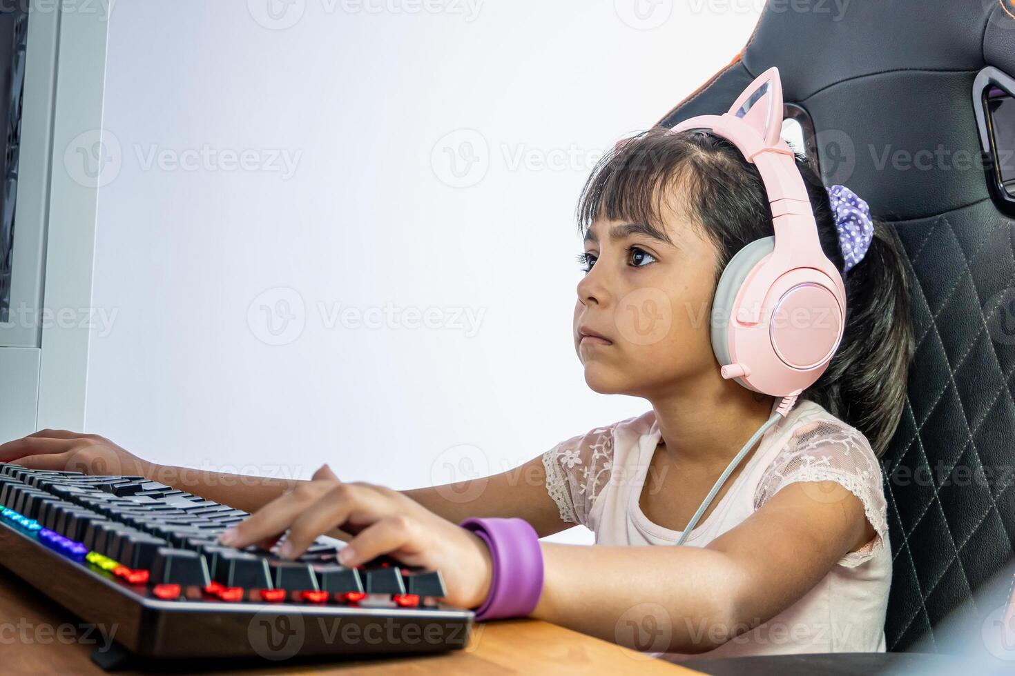 mignonne peu fille en jouant sur le ordinateur dans le chambre photo