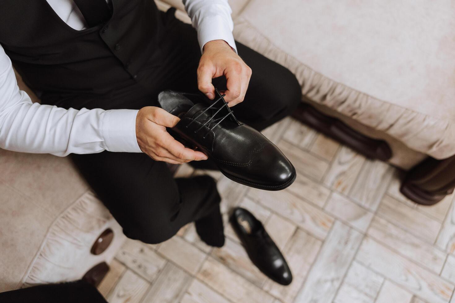 une Jeune homme mettre sur noir cuir bottes à l'intérieur. fermer photo. détail de une jeune marié en mettant sur le sien des chaussures photo