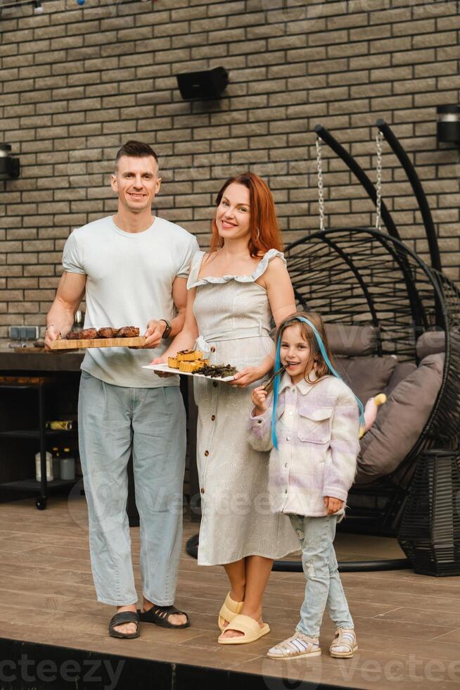 une content famille a préparé le déjeuner et volonté manger à leur maison. portrait de une famille avec nourriture dans leur mains photo