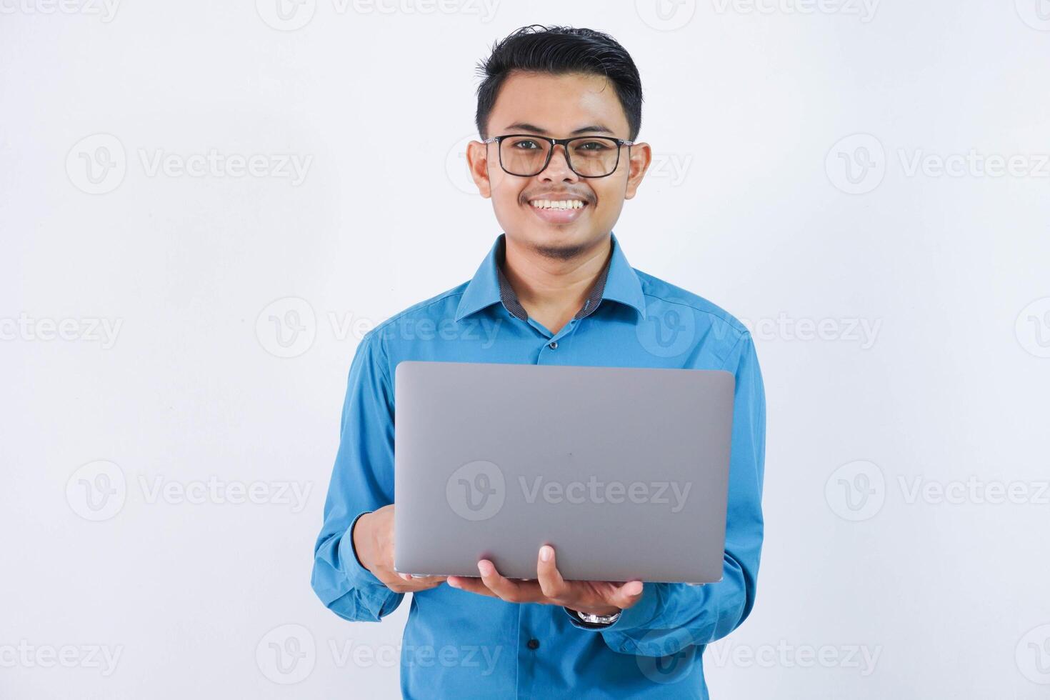 souriant ou content asiatique homme d'affaire avec des lunettes en portant portable portant bleu chemise isolé sur blanc Contexte photo