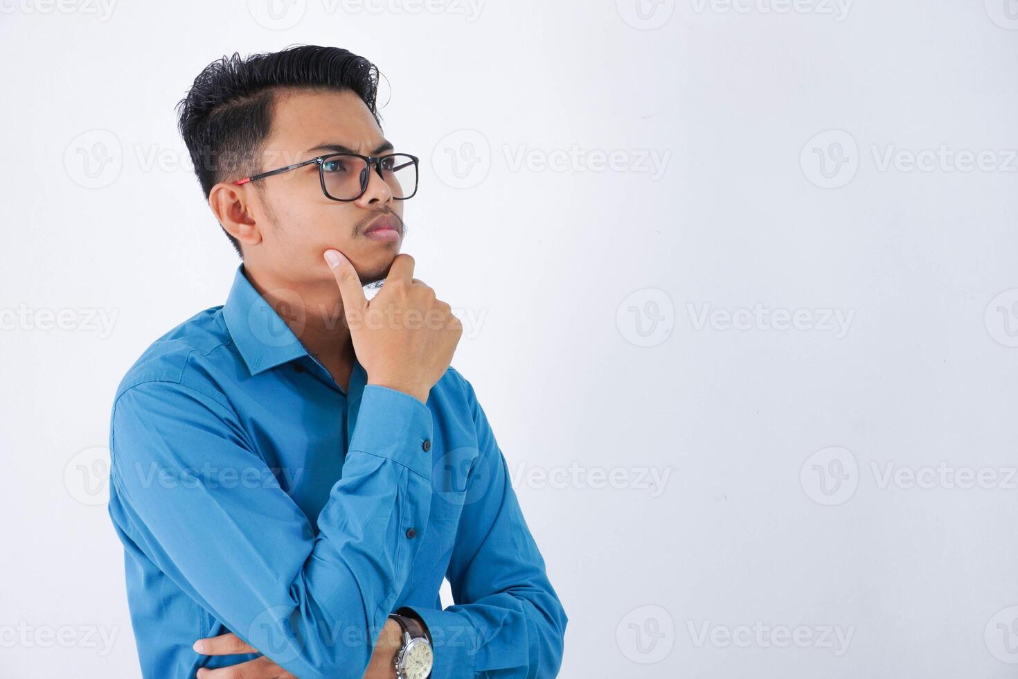 en pensant asiatique homme d'affaire avec des lunettes en portant une menton portant bleu chemise isolé sur blanc Contexte photo