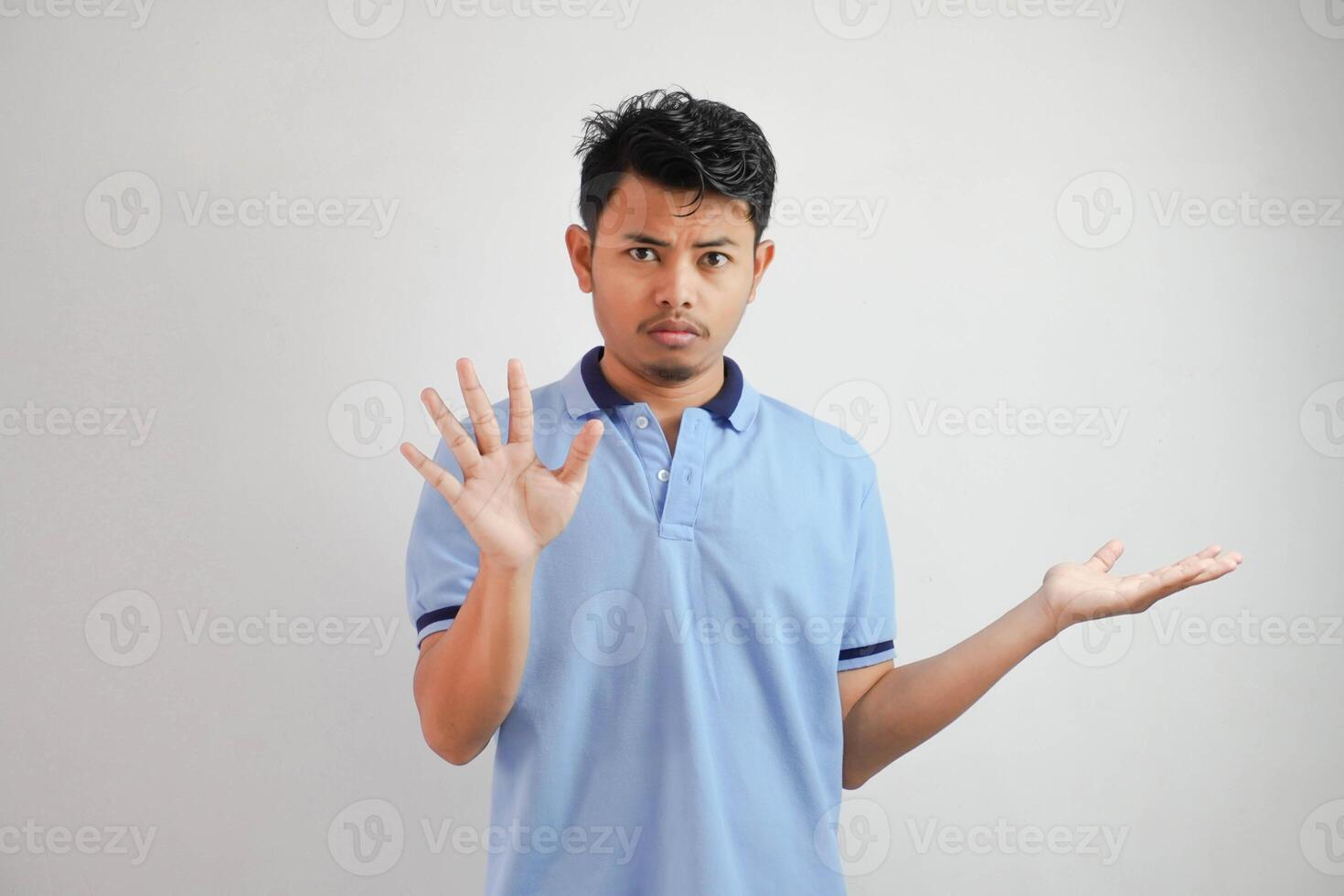 attrayant asiatique homme avec main geste pose rejet ou interdiction tandis que montrer du doigt à copie espace par le sien côté portant bleu t chemise isolé sur blanc Contexte photo
