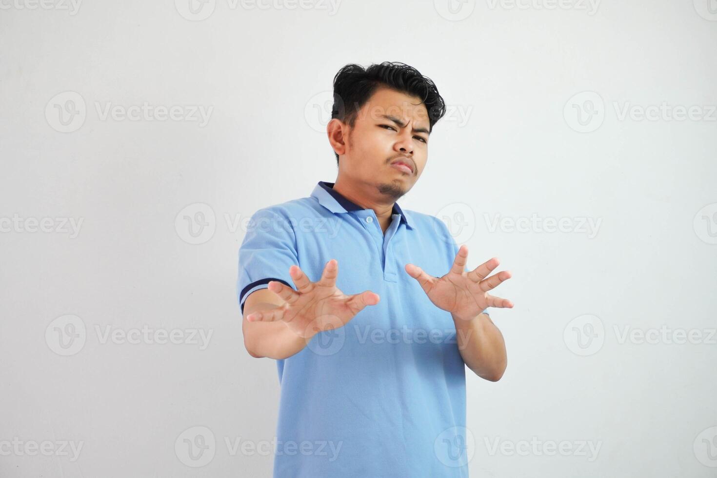 attrayant asiatique homme avec main geste pose rejet ou interdiction tandis que montrer du doigt à copie espace par le sien de face portant bleu t chemise isolé sur blanc Contexte photo