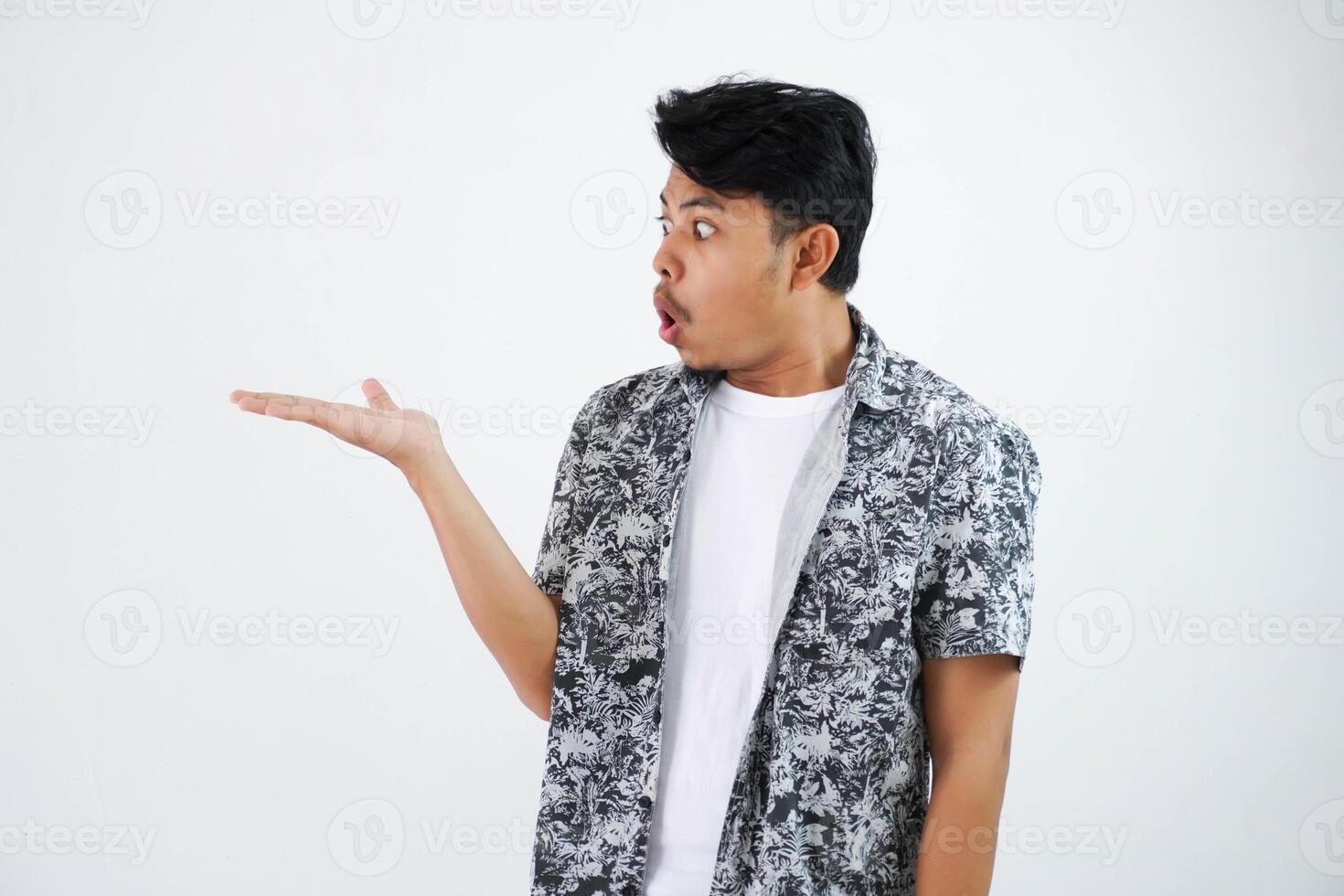 sous le choc asiatique homme avec les doigts montrer du doigt à le côté portant noir chemise isolé sur blanc Contexte photo