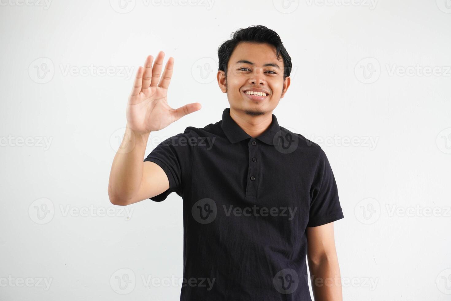 Jeune asiatique homme montrant excité expression lorsque agitant main à saluer Quelqu'un portant noir polo t chemise isolé sur blanc Contexte photo