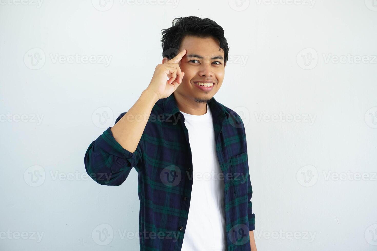 Jeune asiatique homme souriant à le caméra tandis que montrer du doigt à le sien temple isolé sur blanc Contexte. photo