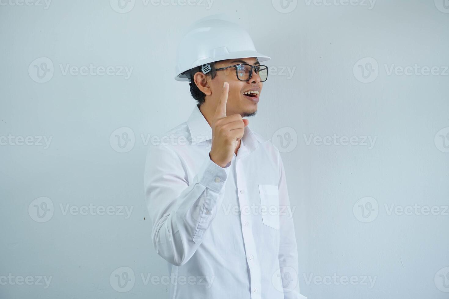 Jeune asiatique architecte homme portant constructeur sécurité casque plus de isolé Contexte montrer du doigt doigt en haut avec réussi idée. sorti et heureux. nombre un. photo