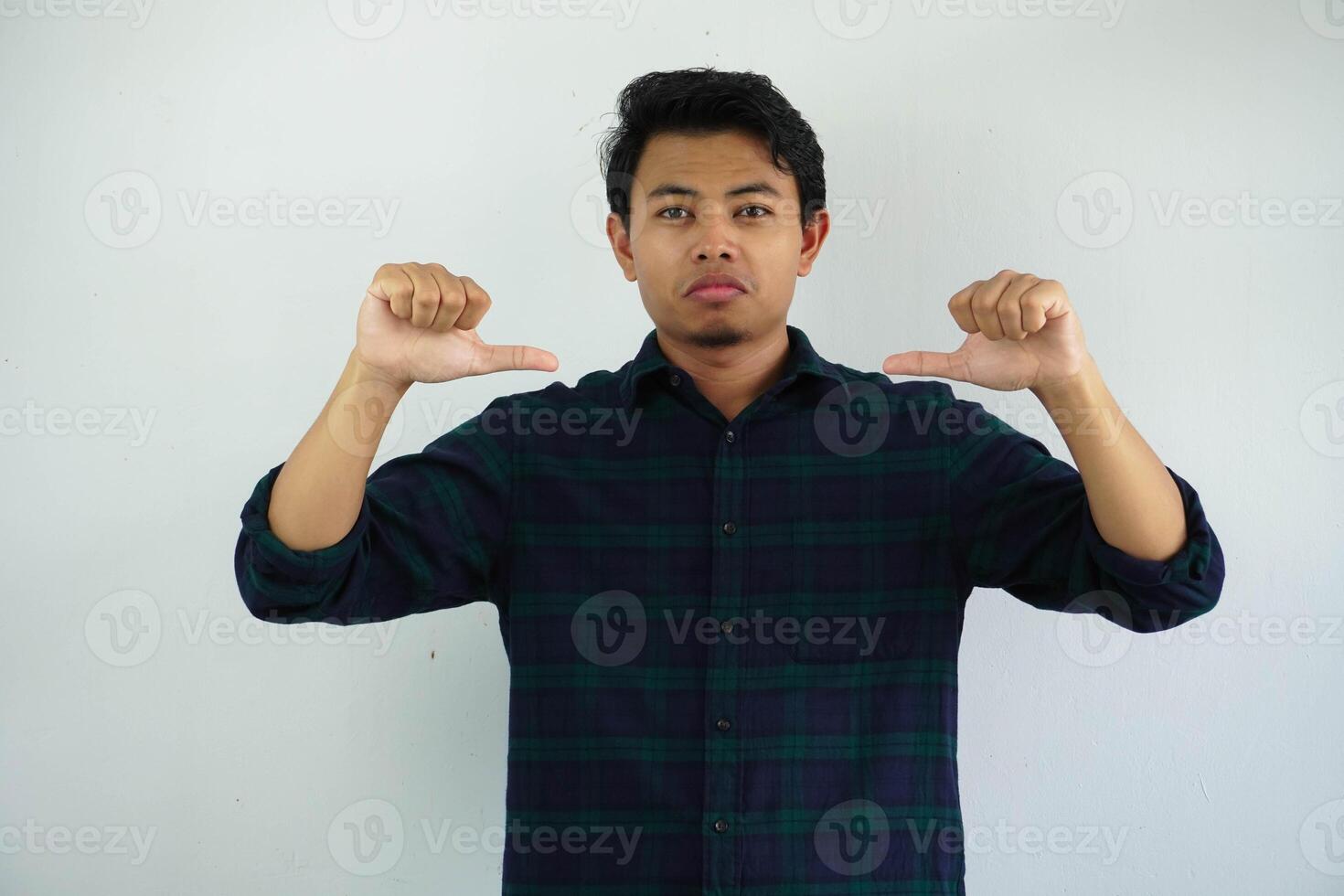 Jeune asiatique homme montrer du doigt le sien soi avec arrogant expression isolé sur blanc Contexte. photo