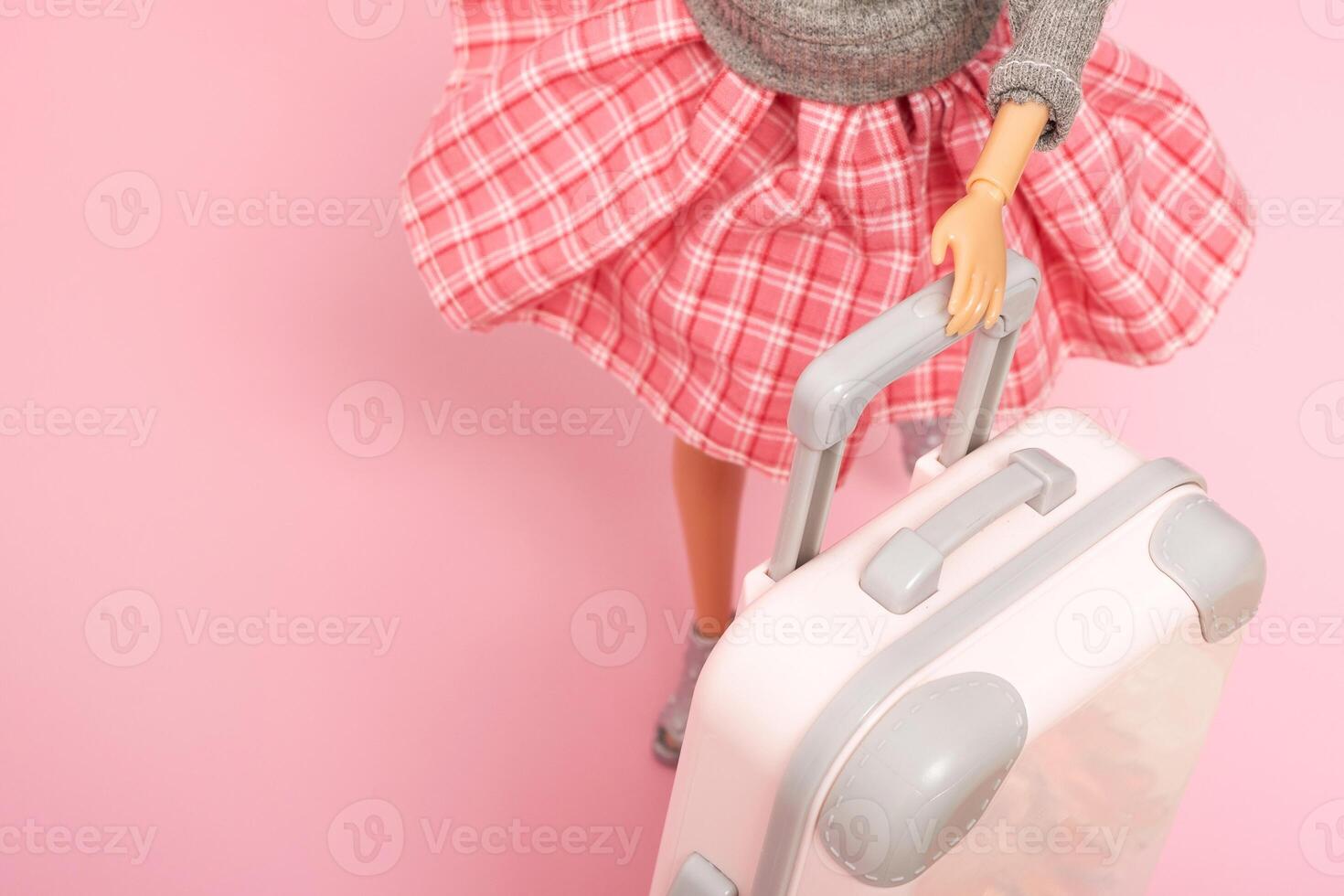 le poupée porte une bagage sur roues. voyage, vacances Créatif minimaliste concept photo
