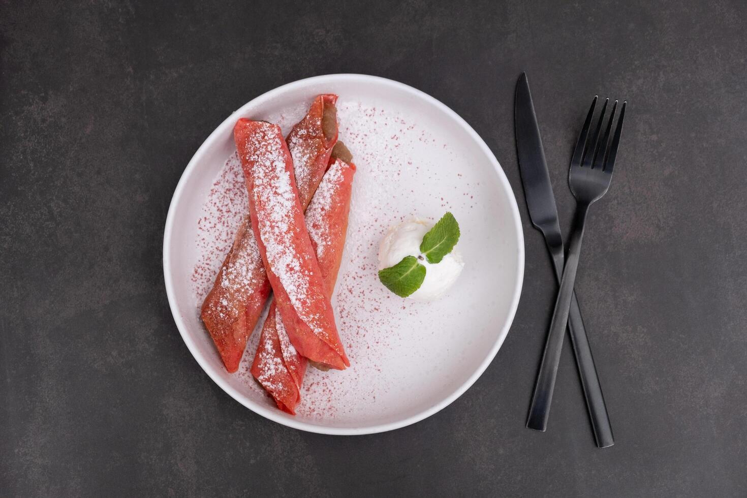 assiette avec sucré rose Crêpes et la glace crème Haut vue sur foncé Contexte photo