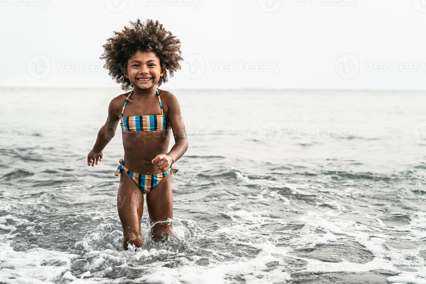 afro enfant ayant amusement en jouant à l'intérieur mer l'eau pendant été vacances. enfance et Voyage vacances concept ré photo