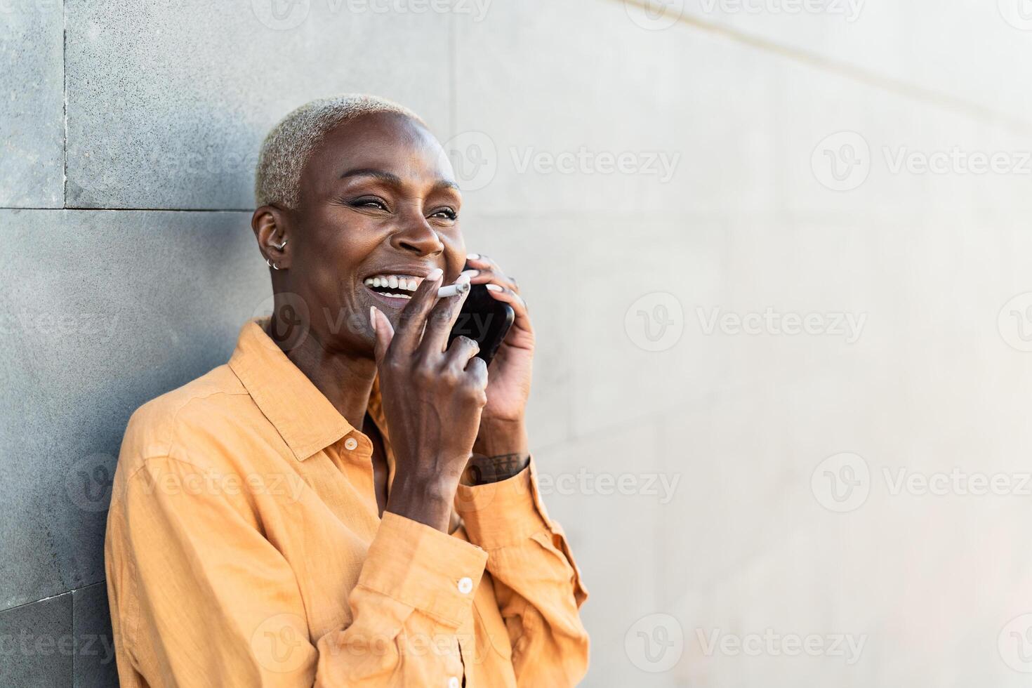africain Sénior femme Faire une appel avec mobile téléphone intelligent tandis que fumeur cigarette photo